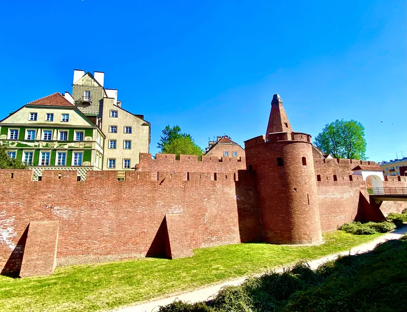 Barbakan Warszawski wiosna - widok na ceglane mury i zielen