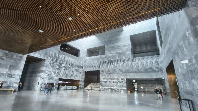 Hol glowny Muzeum Historii Polski - monumentalne marmurowe sciany, zloty sufit kratowy i przestrzen wystawowa