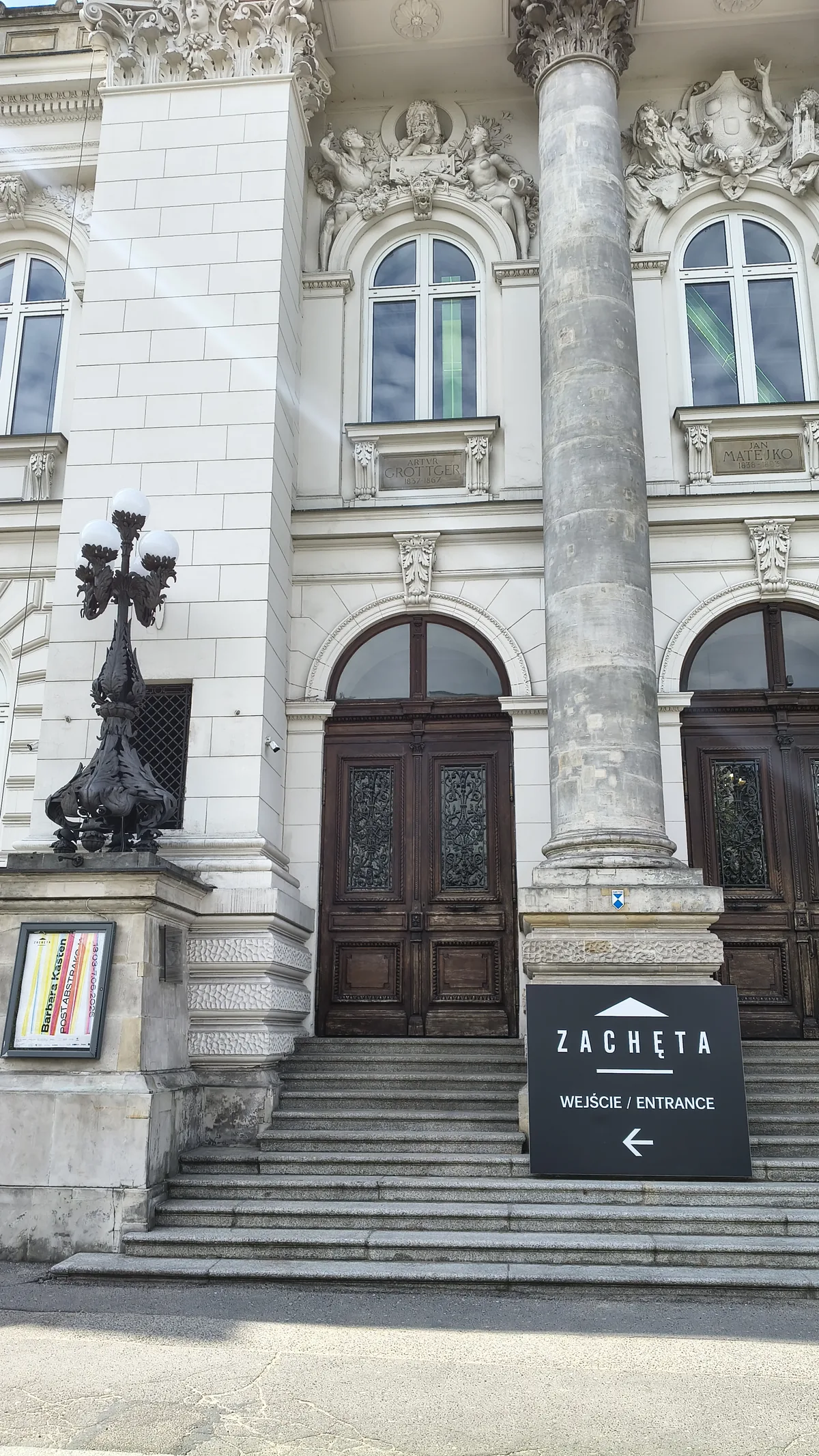 Wejscie do Zachety - masywne drewniane drzwi, kolumna, tablica z napisem ZACHĘTA WEJŚCIE/ENTRANCE